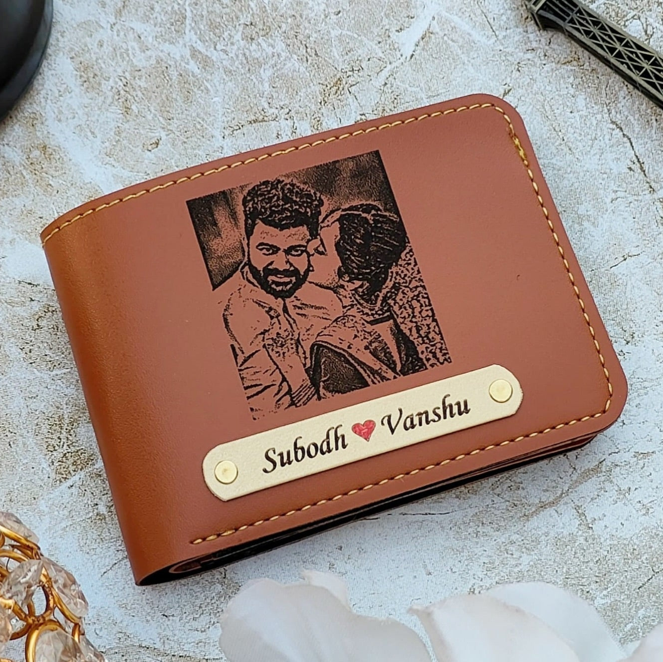 Brown leather wallet with engraved photo and names on a light surface